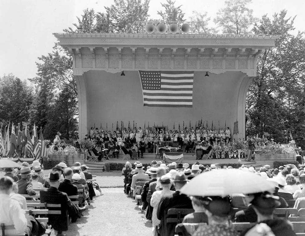 a black and white photo of an old fashioned bandshell with band on stage 