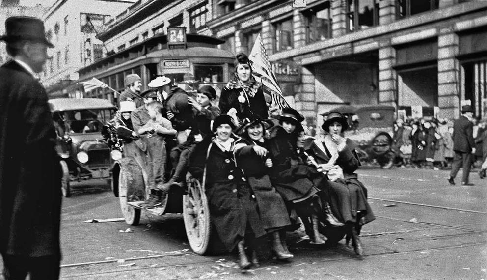 Historical photo from Armistice Day in 1918, with people crowded onto a car in Seattle.