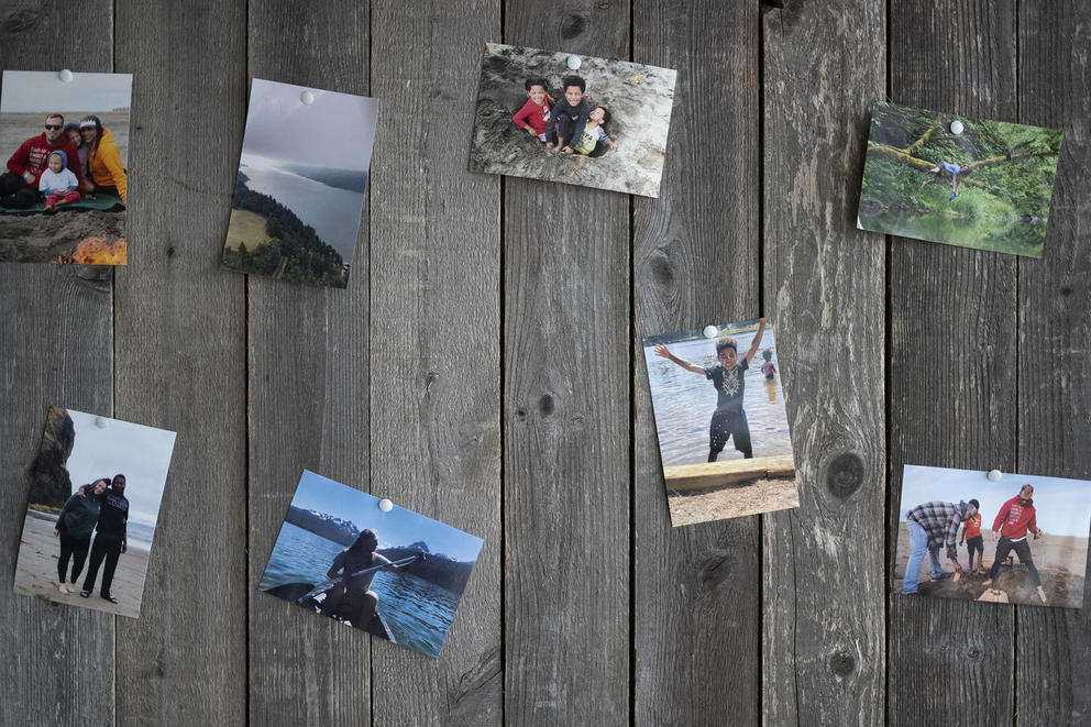 Pinned up photos of people and families on the beach, in a river, climbing trees, and hiking