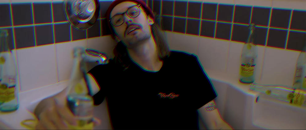 screen grab from a video showing a white man in a bathtub surrounded by empty bottles of Topo Chico