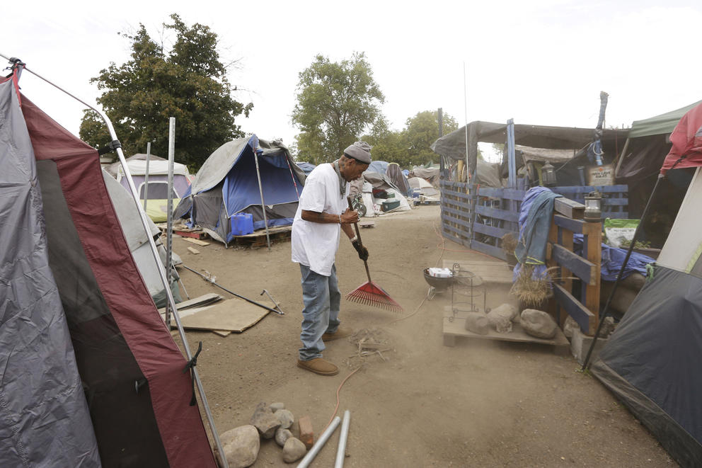 Man cleans a pathway at the Camp Hope encampment 