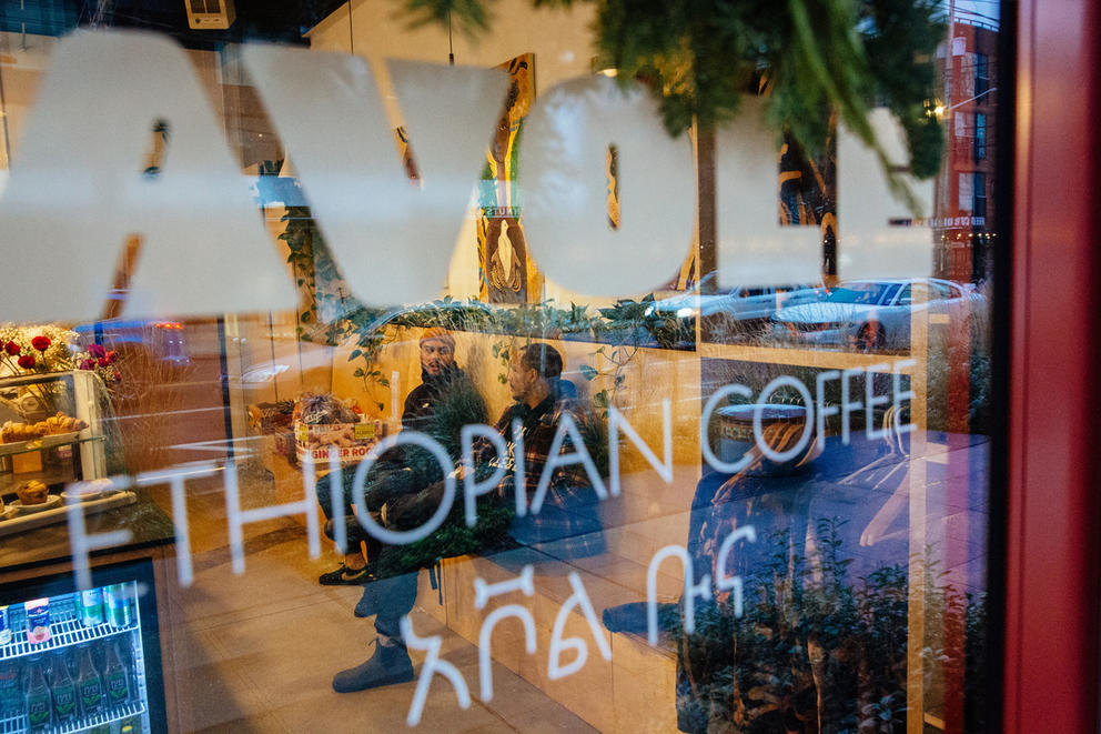 A view through a storefront window of customers seated at a coffee shop