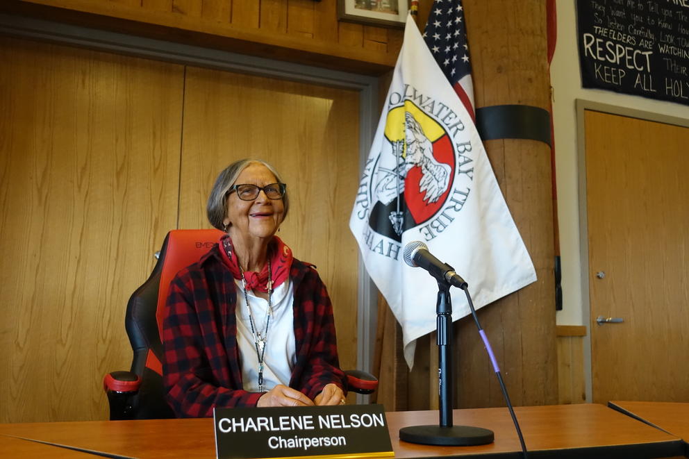 Charlene Nelson sits at a table with a microphone in front of her