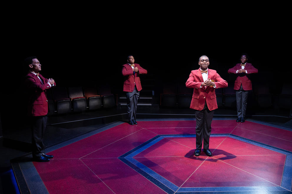 Four men in red blazers perform onstage