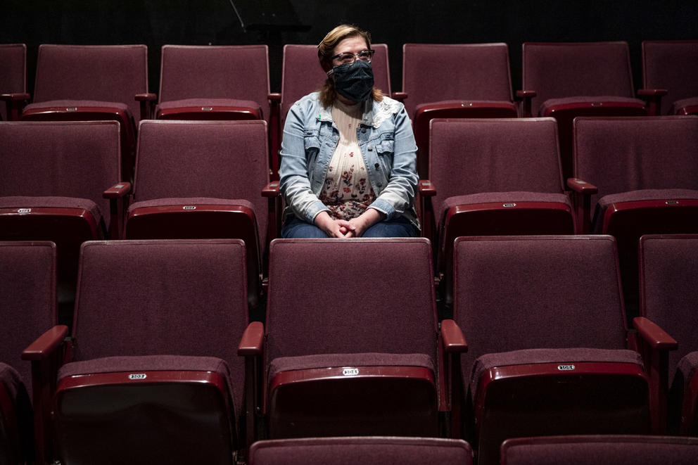 woman in a mask sitting in empty theater seats