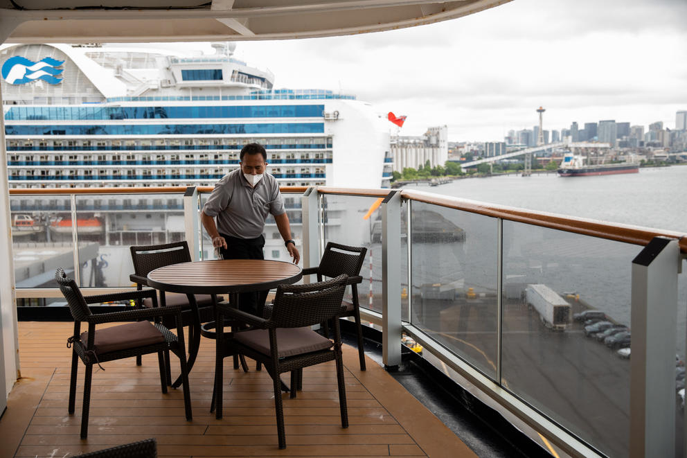Staff clean up a room’s deck furniture on the Holland America Line’s Eurodam