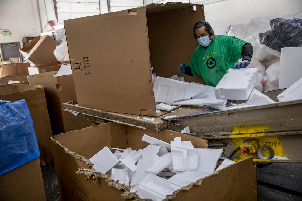 a man sifts through cardboard boxes and Styrofoam blocks