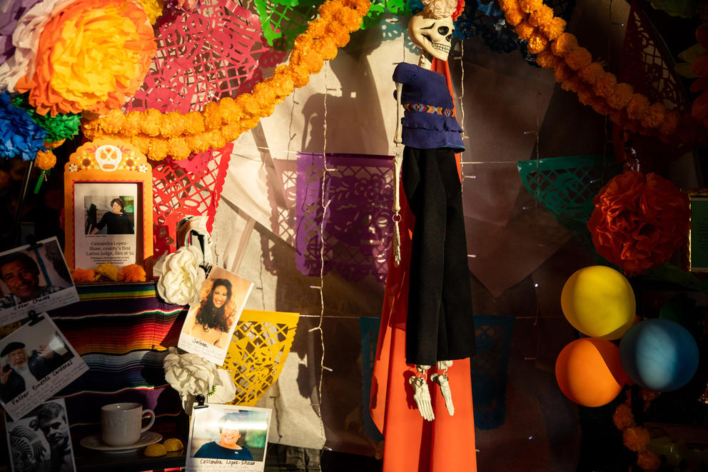 Evening sun lights up an ofrenda with a hanging skeleton and colorful decorations
