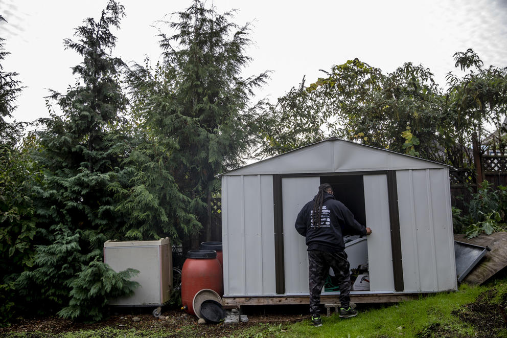 a man enters a gardening shed in a field 