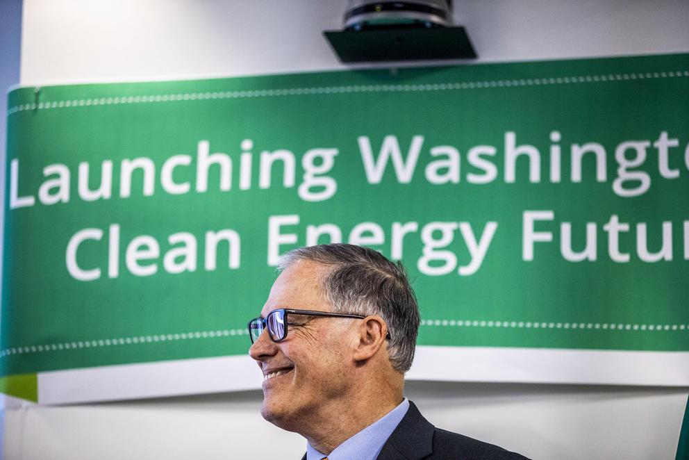Inslee standing in front of a banner reading "Launching Washington Clean Energy Future"