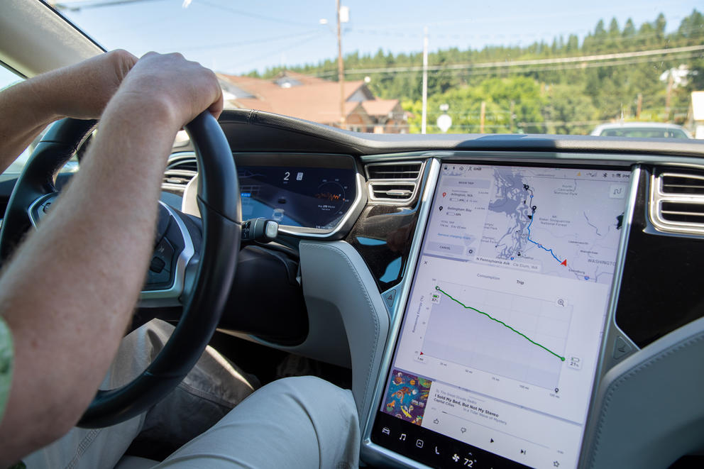 Garrett Brown's arms and steering wheel can be seen next to the dashboard display in his Tesla vehicle.