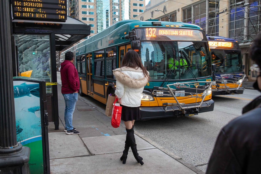 bus riders wait along 34d Avenue in downtown Seattle