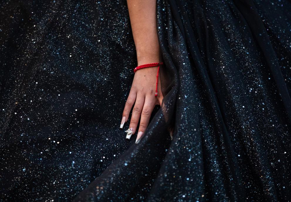 A woman's hand rests against her elaborate dress