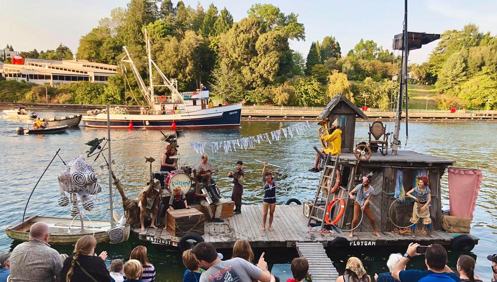 people performing on a ramshackle floating stage