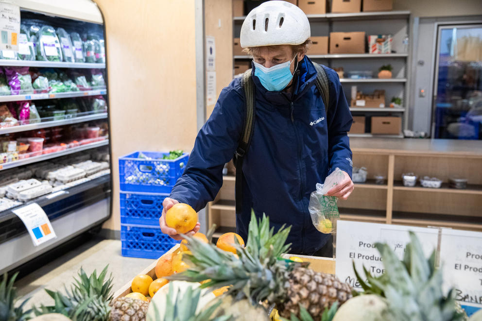 a man picks out fruit from a bin at the ballard food bank