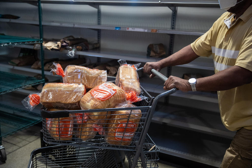 a man pushes a shopping cart full of bread