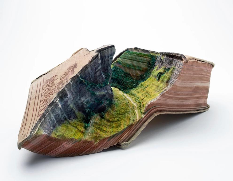a sculpture of a lush green valley carved into a vintage book