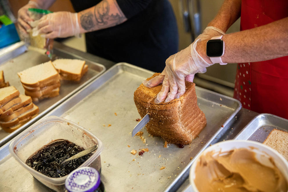 A person slices bread for sandwiches.