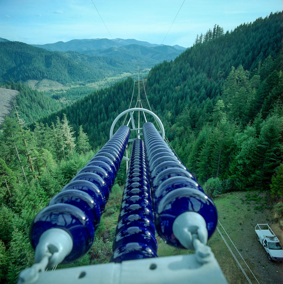 A large electical line stretches toward a forested hill