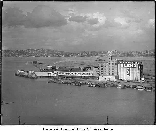 Black and white archival photo of man-made island featuring large industrial buildings