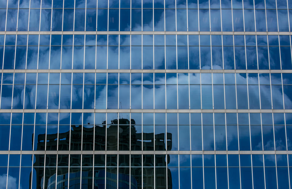 A building is reflected in the windows of another building