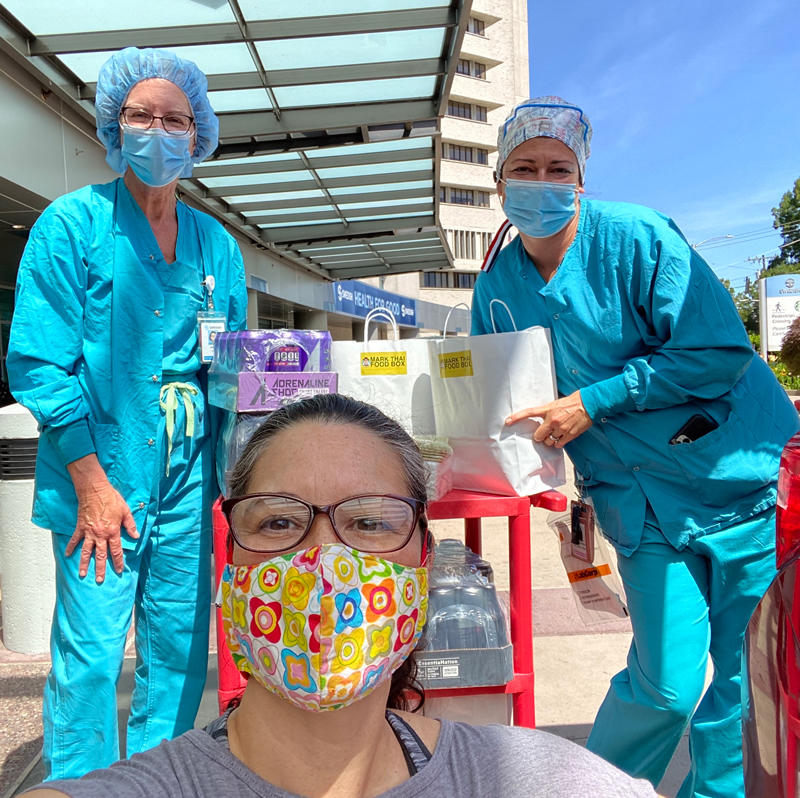 A woman in a face mask poses with medical workers
