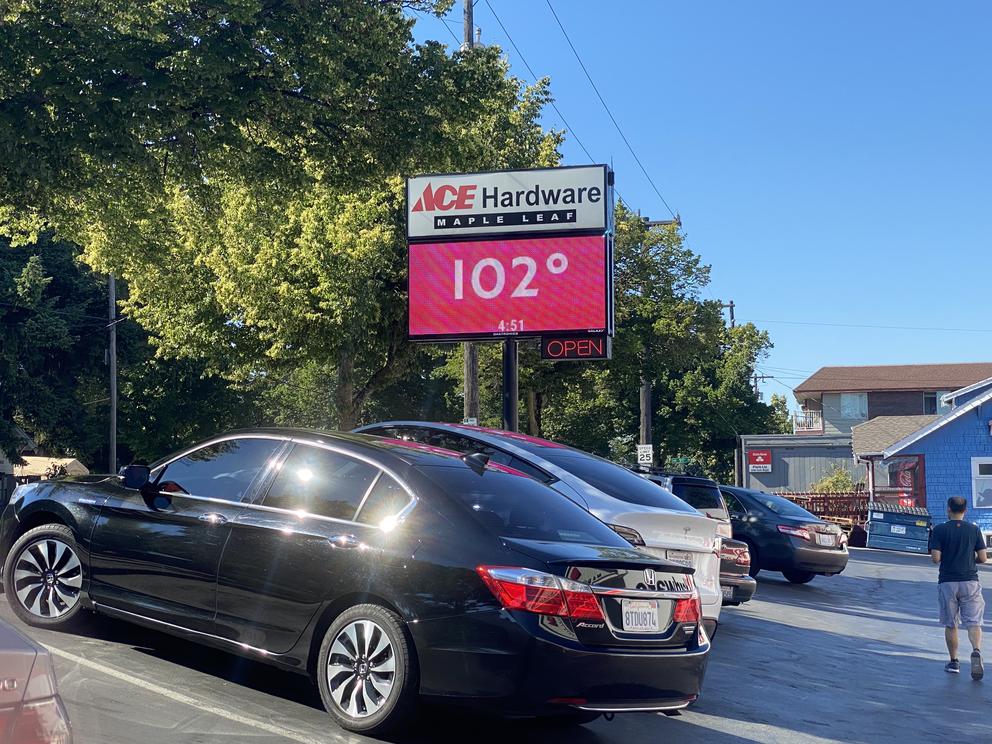 a sign showing the temperature outside a hardware store on a hot day 