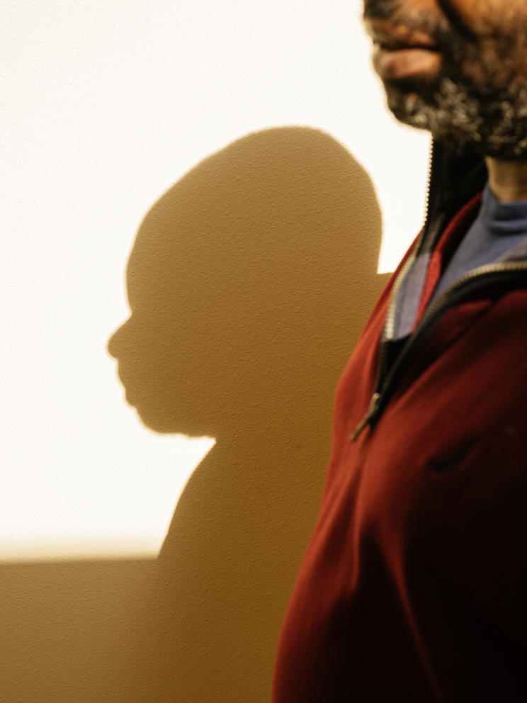 Part of a man's face and his shadow on the wall