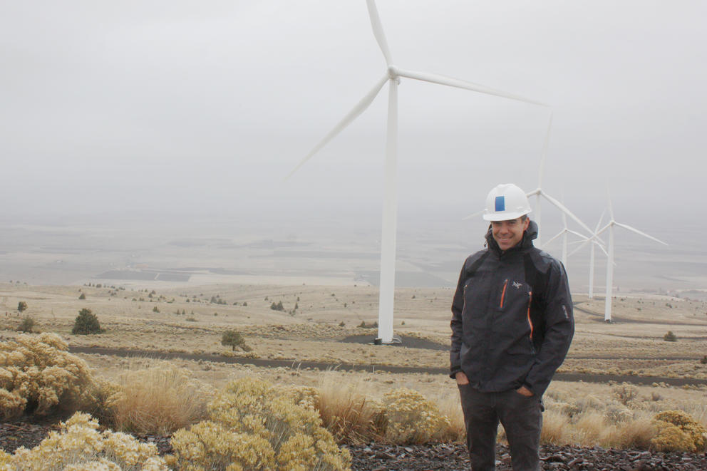 Erik Steimle standing in an open area. A wind turbine stands in the distance
