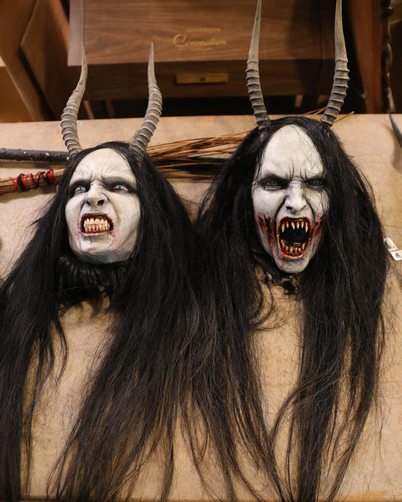 horned Krampus masks with long black hair lie on a table