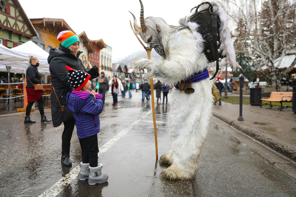 Children talking to a man dressed in a Krampus costume and mask