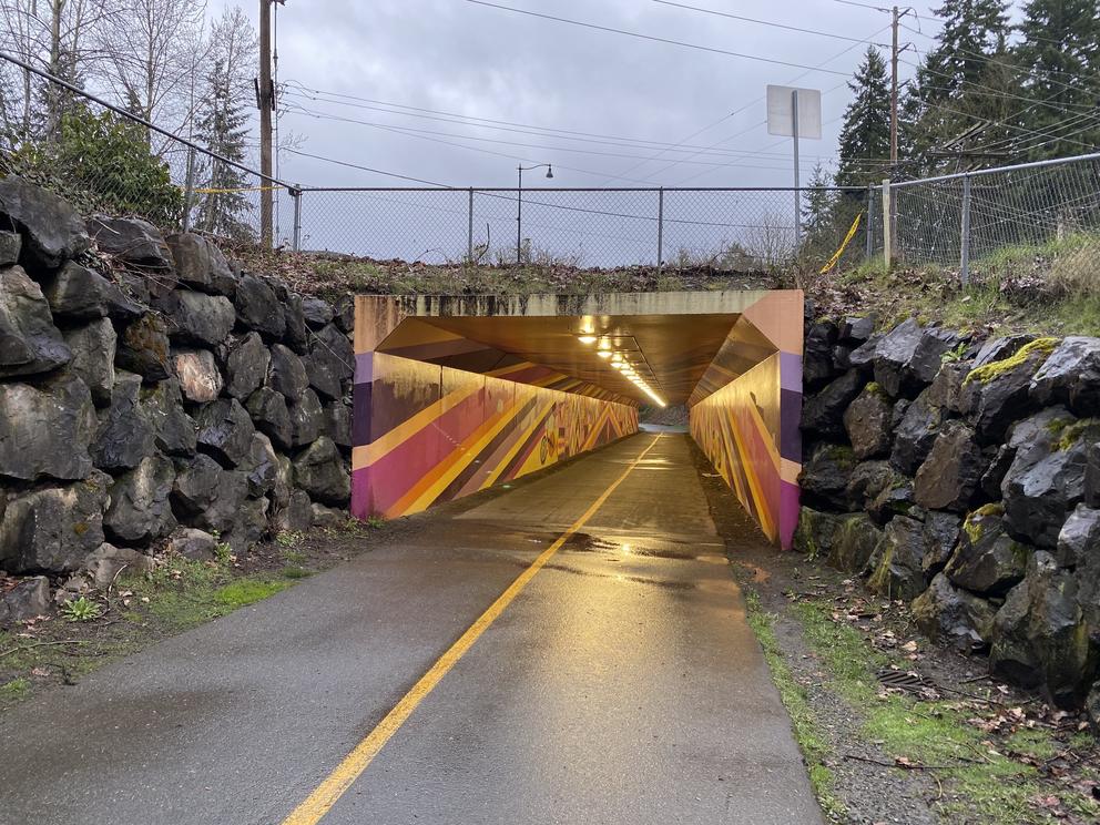 a pedestrian tunnel along a bike trail, walls and ceiling painted in orange and purple stripes