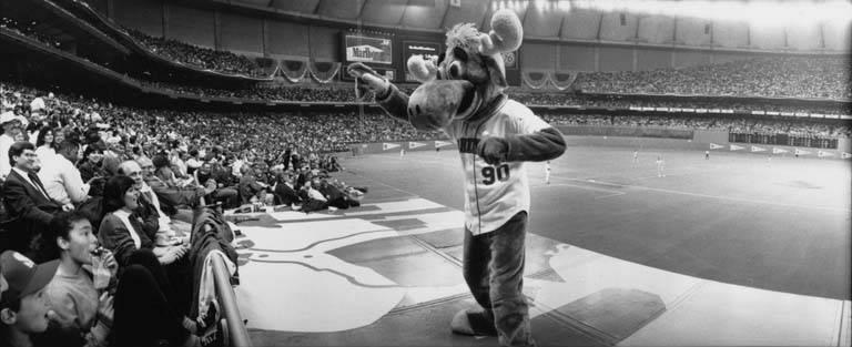 a black and white photo of Mariner Moose in front of a crowd at a baseball stadium