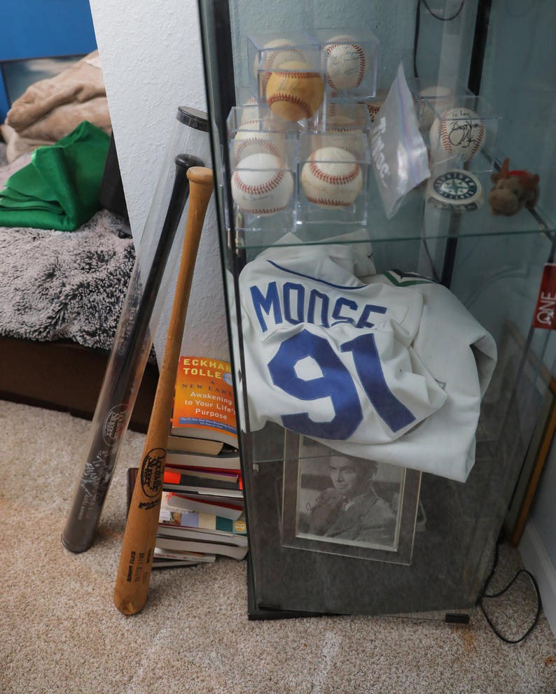 A display case with baseball bats, a jersey and autographed baseballs in it
