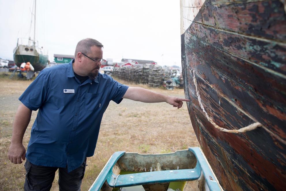 Troy Wood, derelict vessel removal program manager for the state Department of Natural Resources, points out damage on an aging wooden-hulled vessel that could be a “future customer” of a boat recycling center in Ilwaco, Washington.