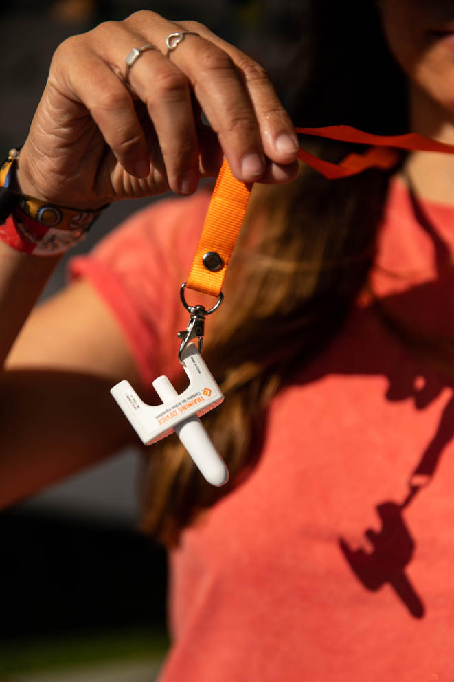 Person holds up orange ribbon with white nozzle attached