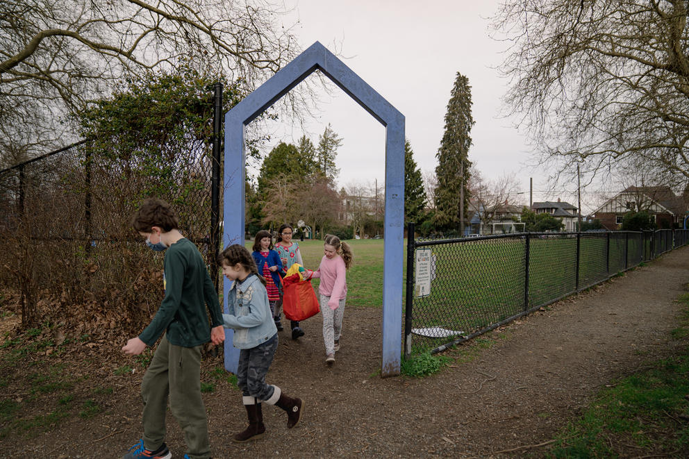 Young students leave a park through an archway.