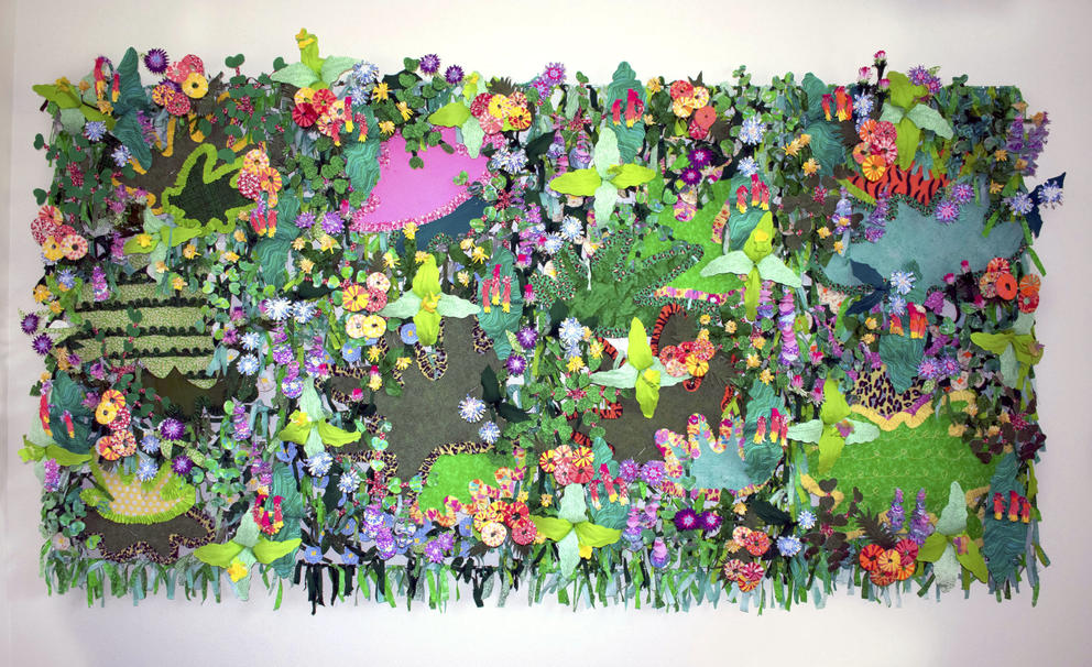 A collage fabric jungle wall with different types and colors of flowers, leaves and greenery as well as patches of animal patterns like tiger stripes and cheetah print. 