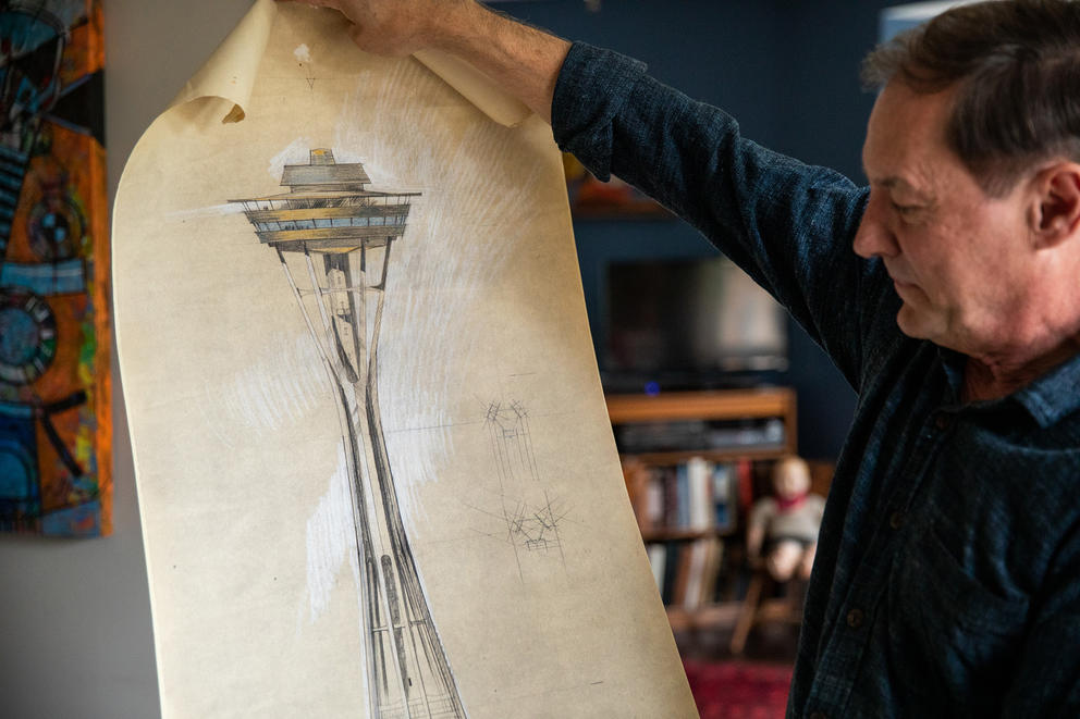 A man unrolls a drawing of the Space Needle