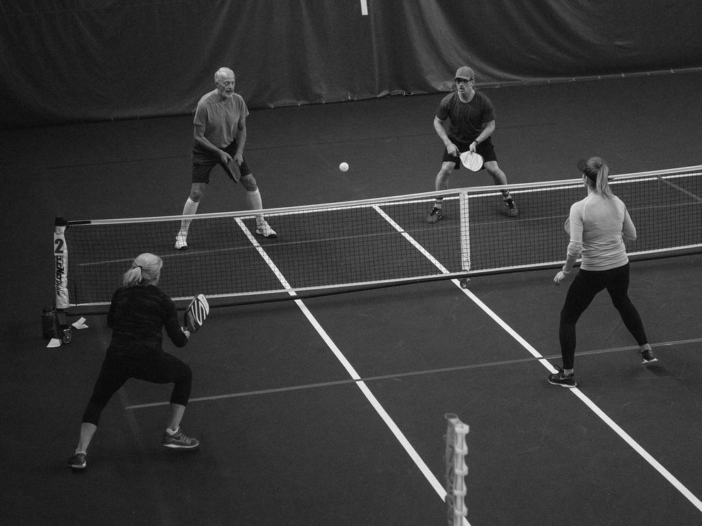 a view from above of four people playing doubles on a pickleball court