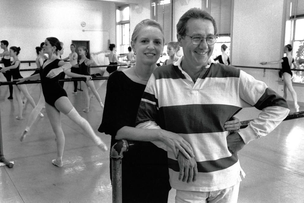 black and white photo in a ballet studio where a woman and man pose in an embrace
