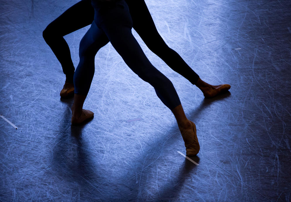 two pairs of legs dance in a room bathing in blue light