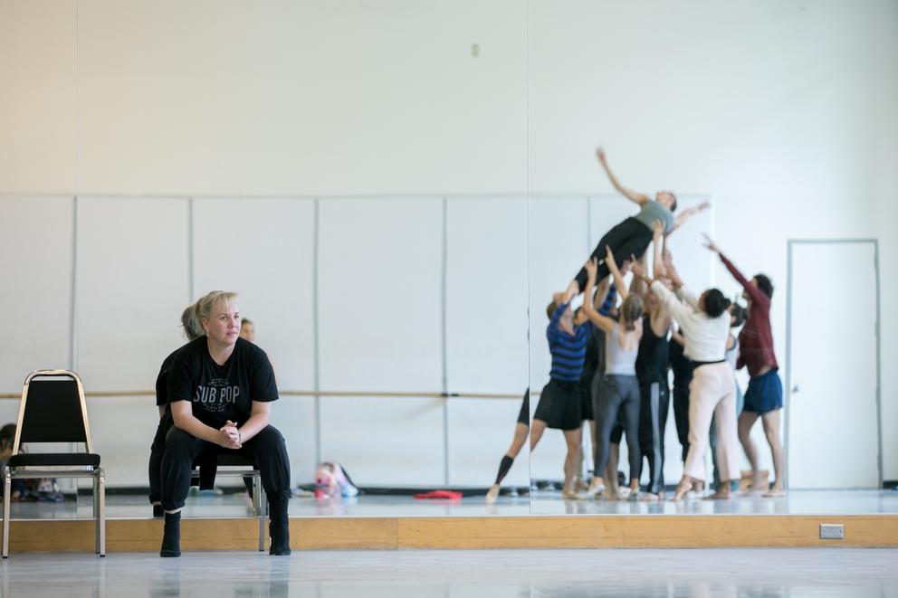 Choreographer Eva Stone sits while watching dancers practice in a mirror