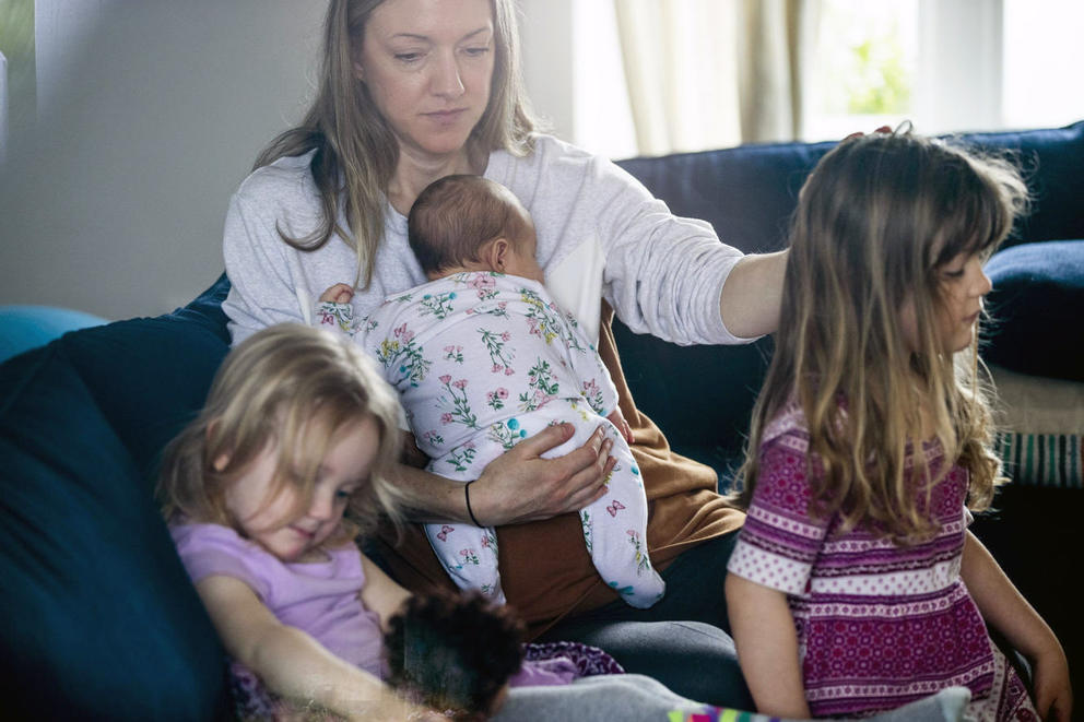 Caitlin Lombardi with her three daughters, from left, two-year-old Alma, five-week-old Pearl and four-year-old Maple sit on a couch together