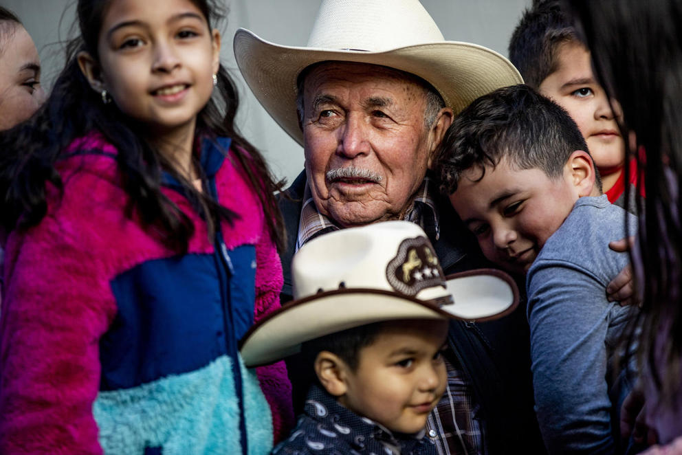 Raul Espinoza Gomez, smiling and wearing a cowboy hat, is surrounded by several of his grand children and great-grandchildren