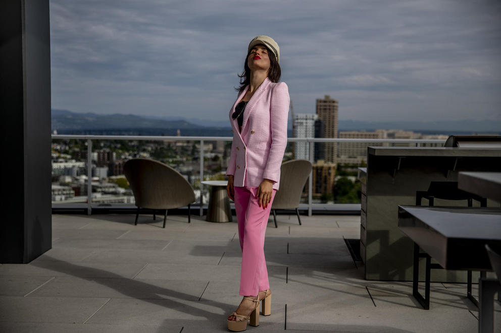 Venus Aoki wearing all pink stands on an outdoor patio with the city in the background