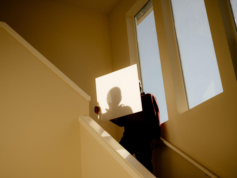 A man is silhouetted against a white piece of paper in a stairwell