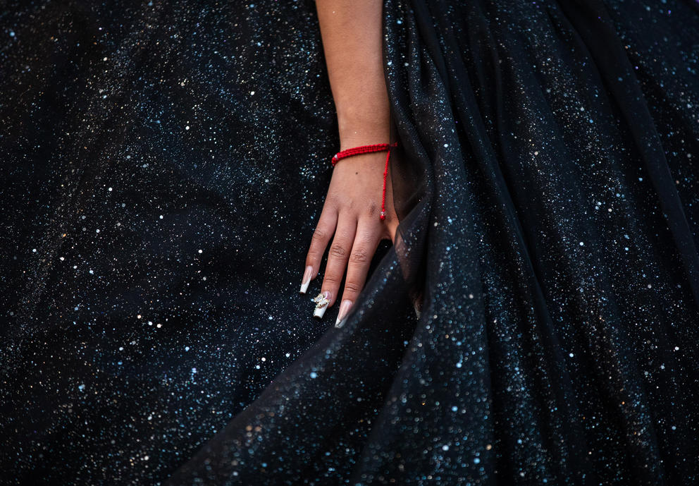 A close up of a hand with painted nails on a black sparkly dress