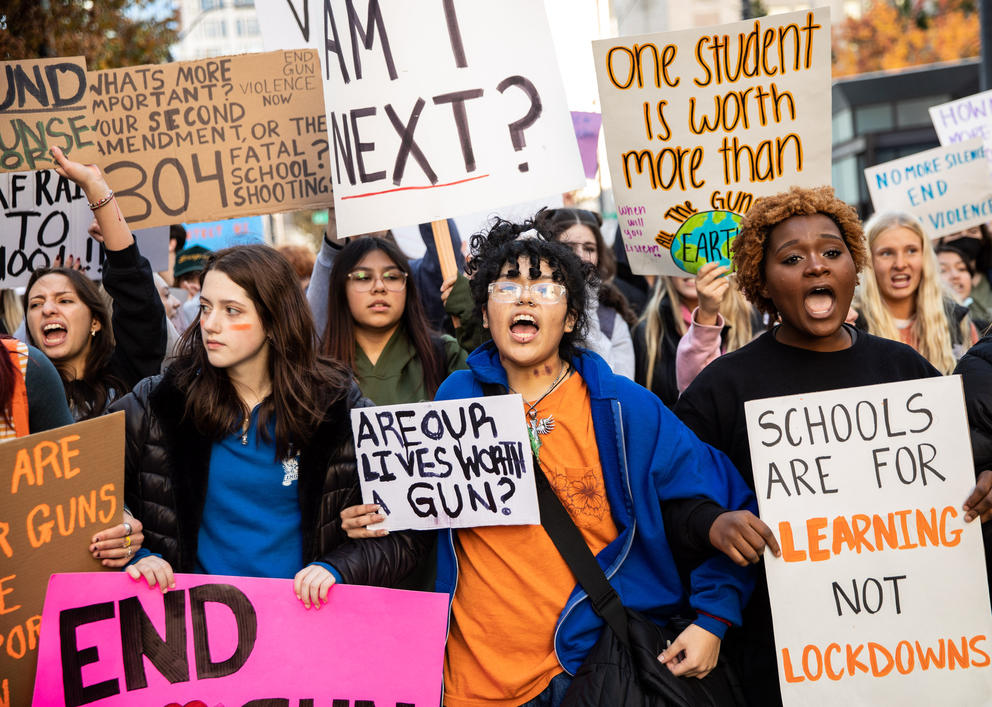 A group of students marches toward the camera holding signs
