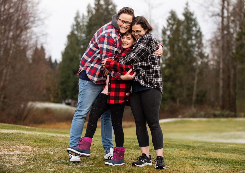 The Cofer family hugs each other with their daughter in the middle, posing in an open field